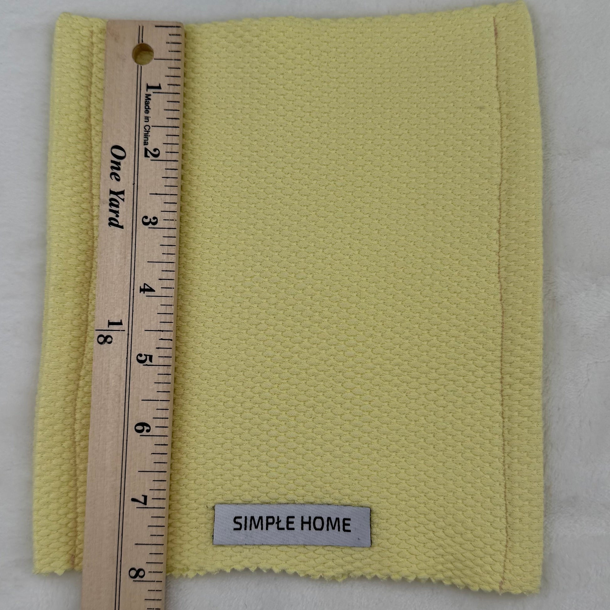 Yellow fabric swatch with a ruler and 'Simple Home' label on a gray background