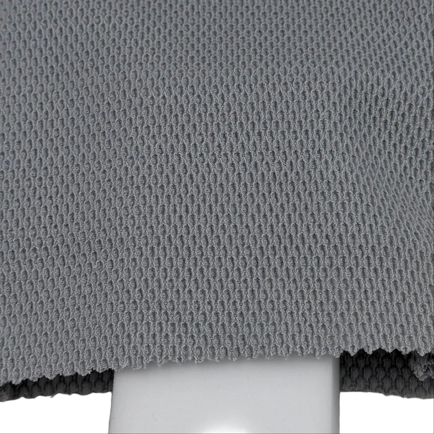 Gray cleaning pad with bristle brush and white foam block on a light gray background