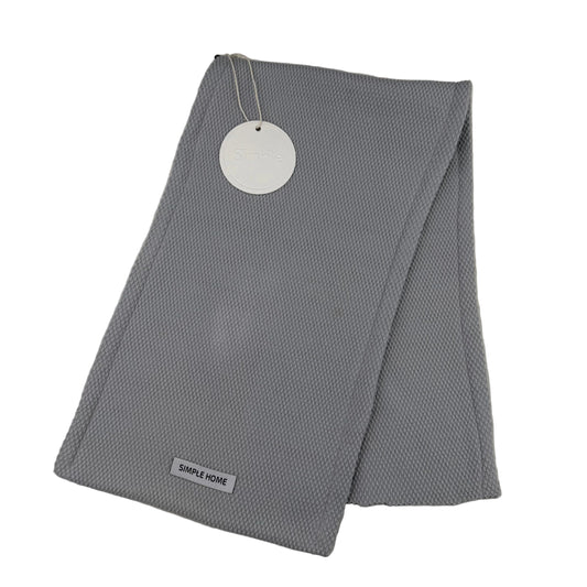 Folded gray textured tea towel with a tag on a light gray background