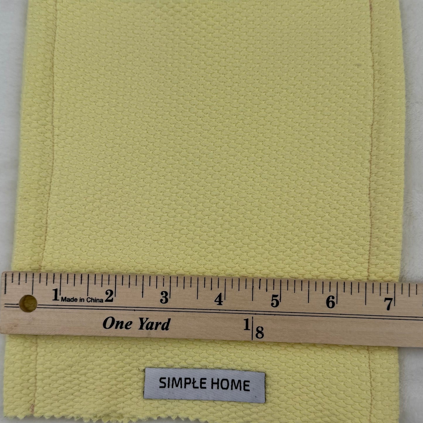 Yellow fabric swatch with a ruler and 'Simple Home' label on a gray background