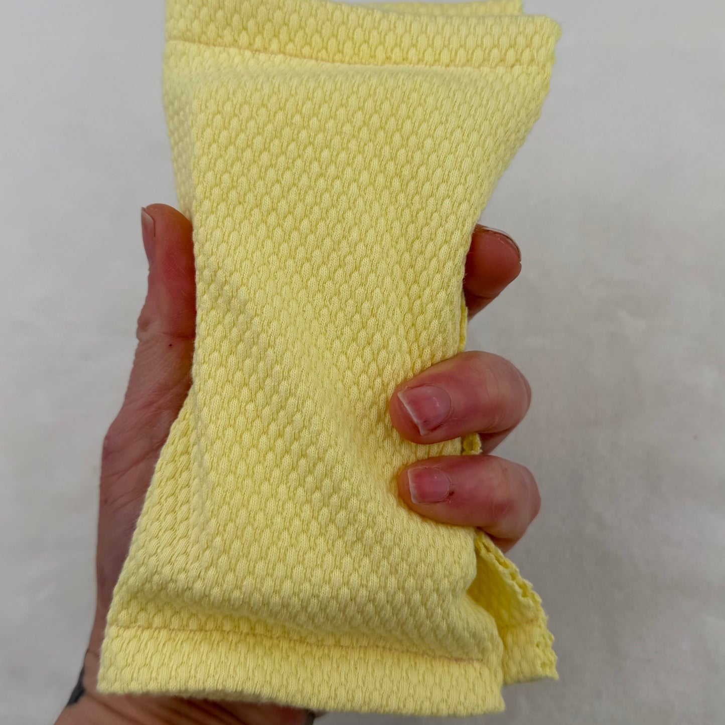 Hand holding a yellow textured square against a plain background