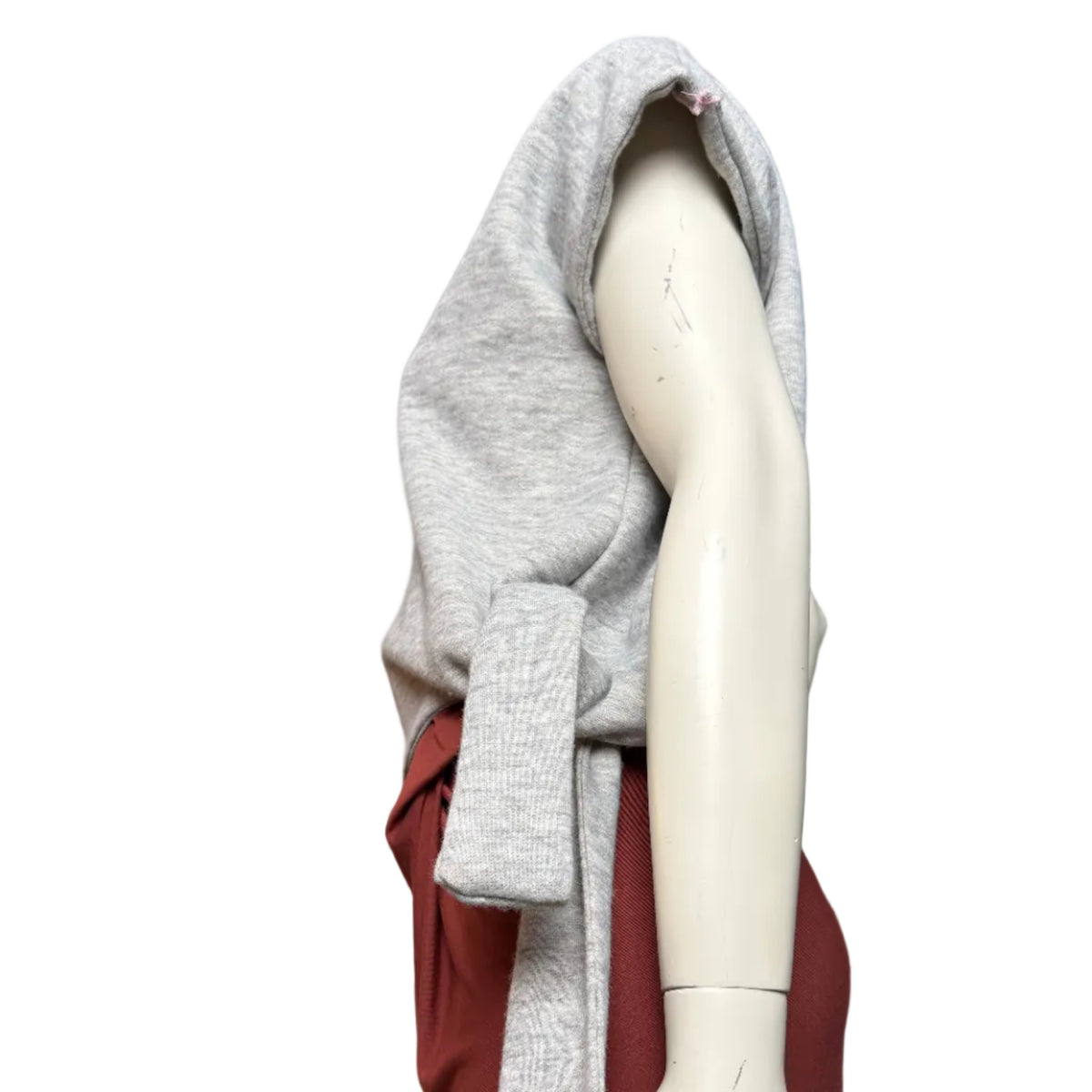 A light gray heather knit wrap or shawl draped over a cream mannequin arm, with a rust red fabric layer visible underneath, photographed against a plain white background.