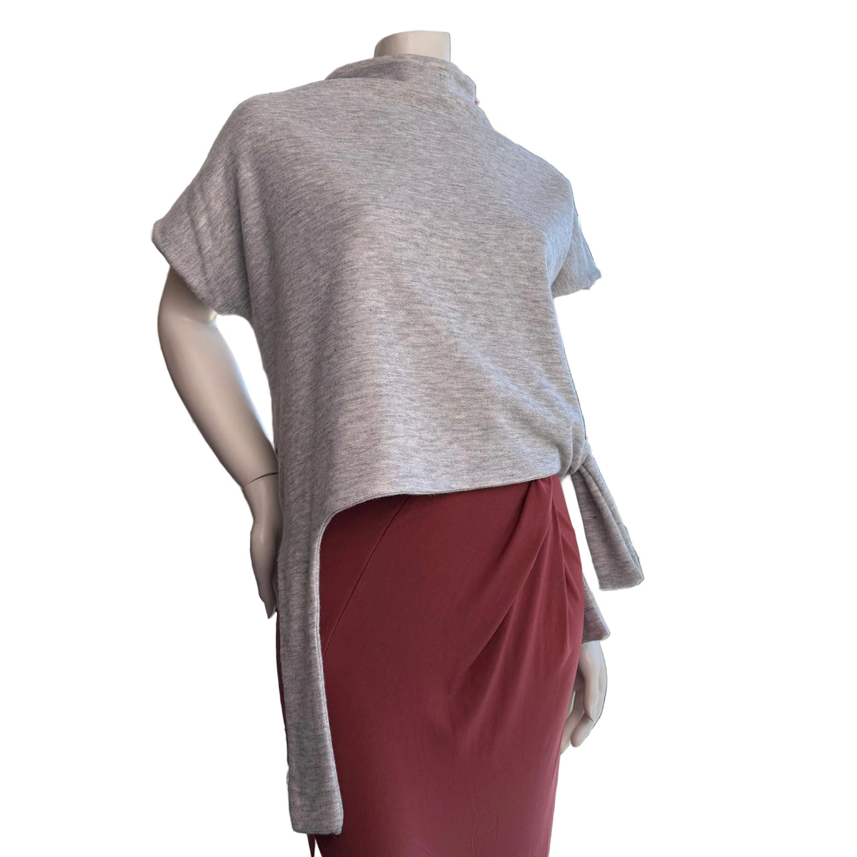 Mannequin wearing a gray top and red skirt in an outdoor setting with a view of trees and sky.