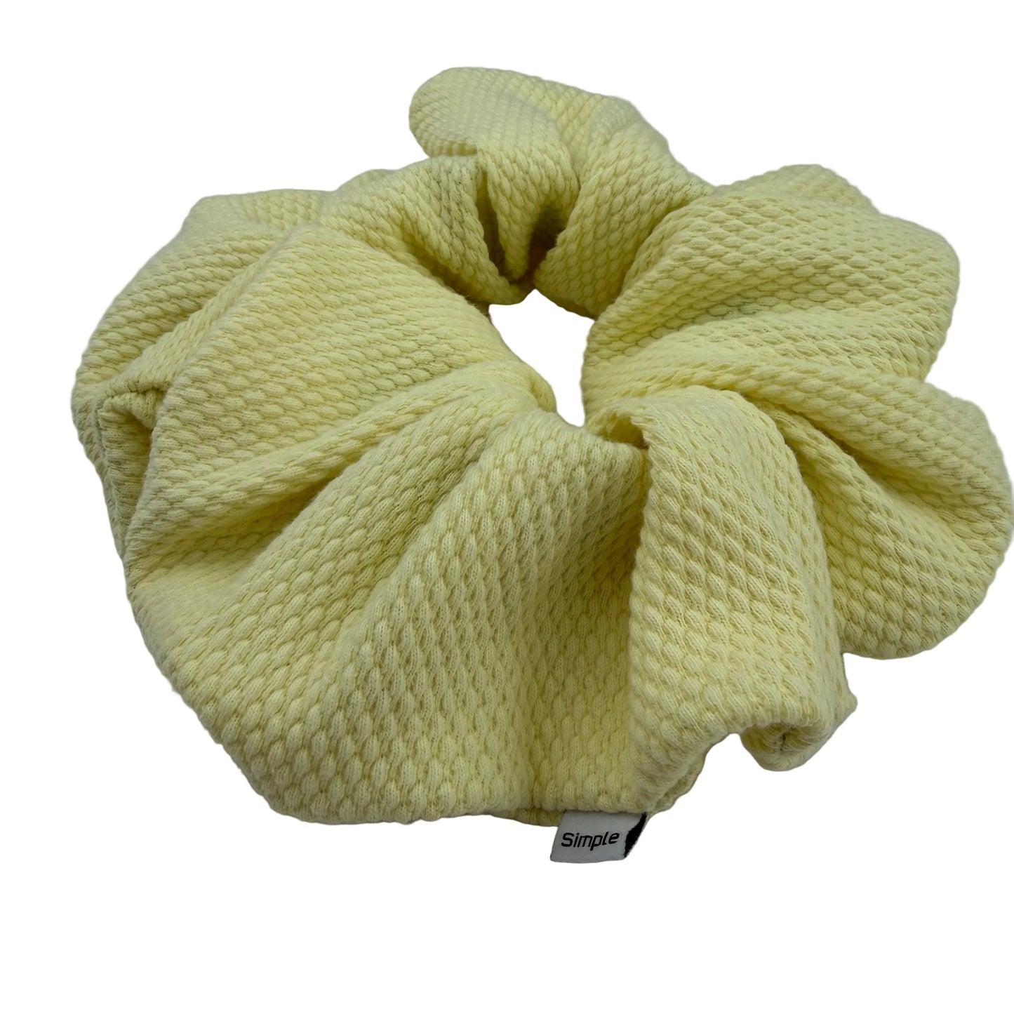 Yellow scrunchie with a brand label on a light gray background