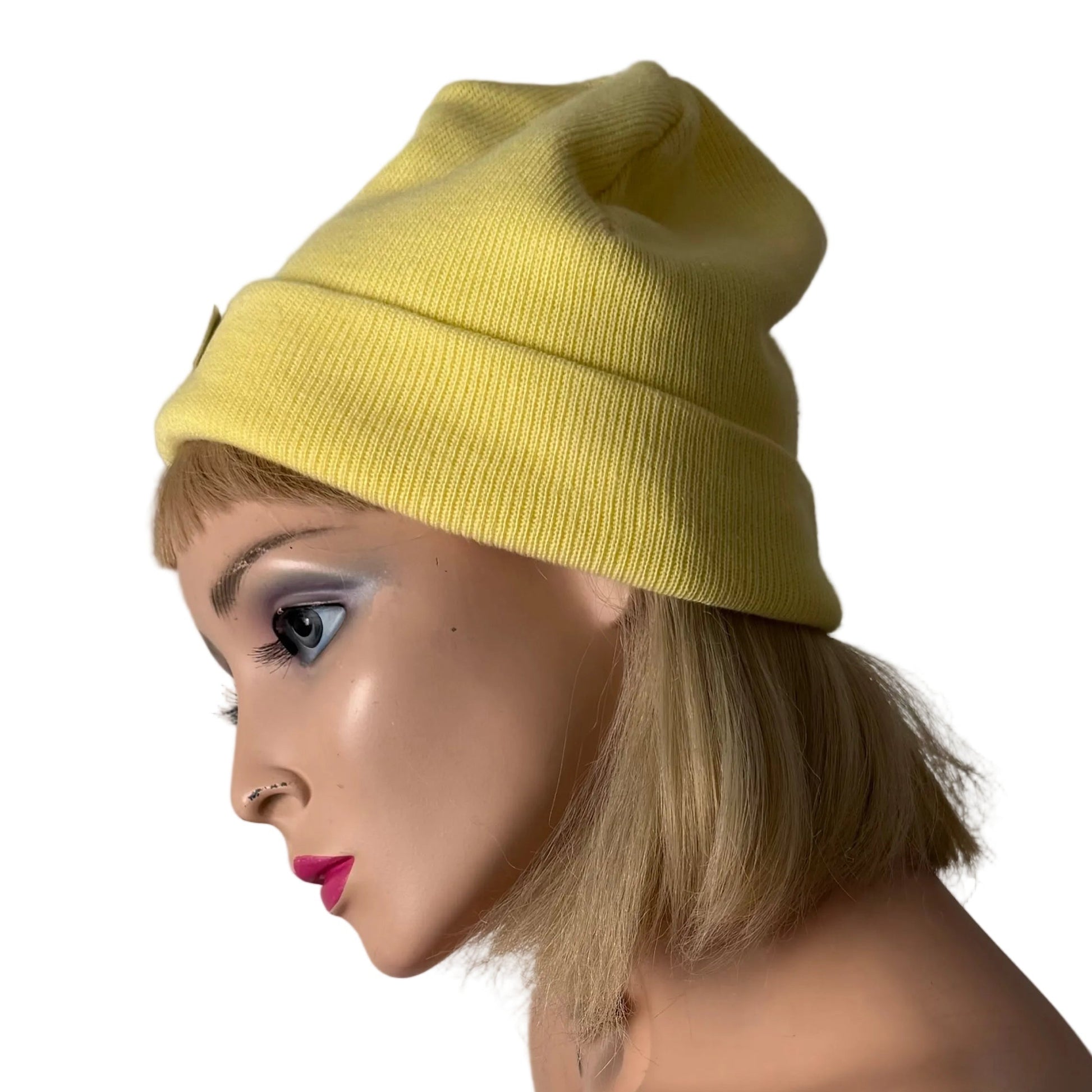 Mannequin wearing a yellow beanie and pink top against a neutral background